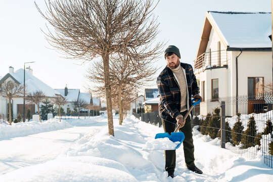 Man shoveling snow from sidewalk in winter neighborhood