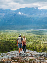 Romantic couple hiking together hugging on the mountain cliff above forest travel vacations tour in...