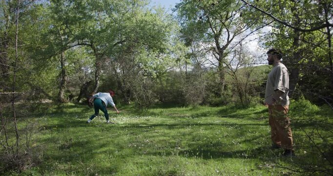Friends Enjoying a Frisbee Game in a Sunny Field Surrounded by Trees