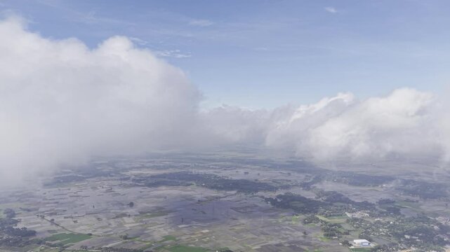 Aerial View of Rural Settlement and Open Fields Beneath Drifting Clouds