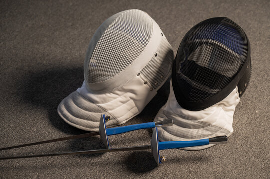 Fencing equipment. Swords and masks on the gray floor.