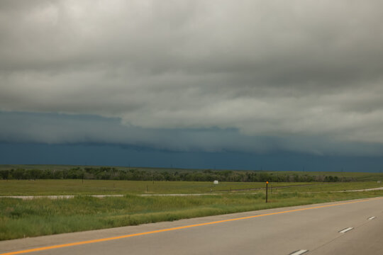 Storm Clouds Over Open Highway Across Flat Plains With Dramatic Dark Sky and Approaching Weather