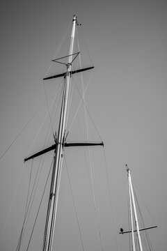 View looking up at old wooden schooner masts in front of the sky