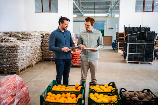 Two men discussing inventory in a fresh produce warehouse