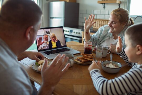 Family video calling grandparents during breakfast at home kitchen