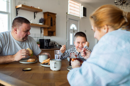 Parents and son having breakfast at home kitchen table