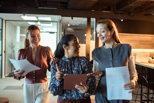 Three businesswomen collaborating with tablet in modern office