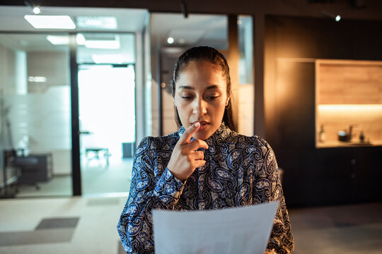 Concerned businesswoman reviewing paperwork in modern office
