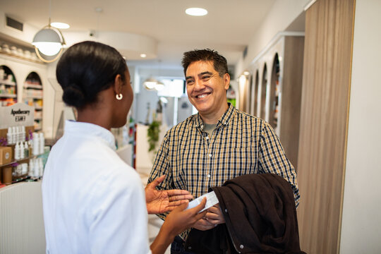 Pharmacist advising customer in modern pharmacy
