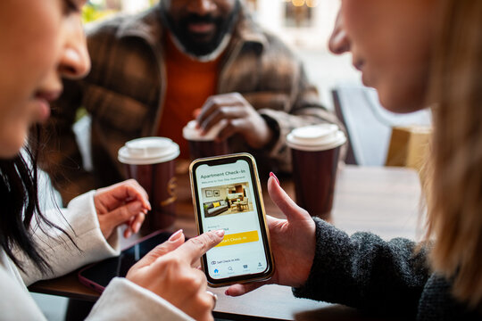 Friends using mobile apartment check-in app at cafe