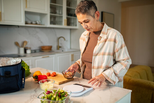 Mature woman weighing ingredients for meal prep in home kitchen