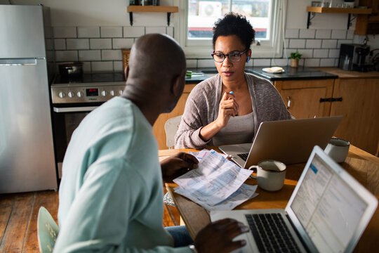 Couple reviewing bills and budgeting at home kitchen table