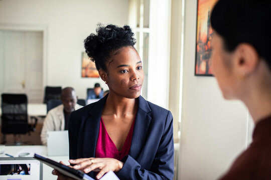 Businesswoman discussing project with colleague in modern office