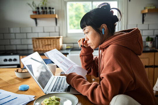 Young woman reviewing bills and budget at home kitchen table
