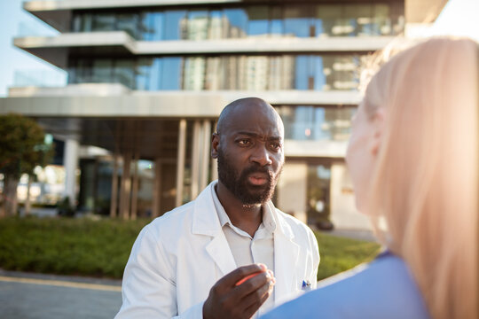 Male doctor discussing with nurse outside hospital