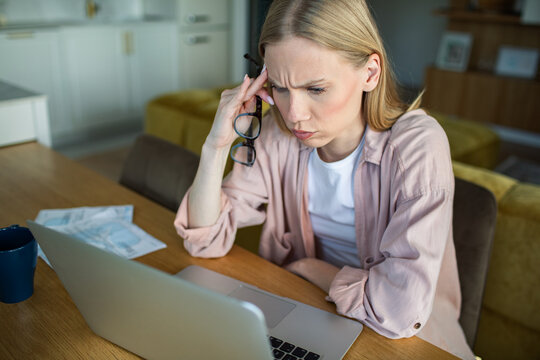 Concerned woman reviewing bills on laptop at home