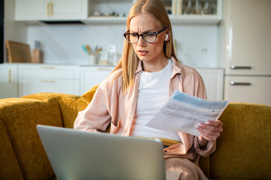 Young woman reviewing bills on laptop at home
