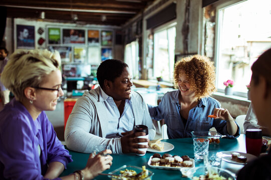 Diverse coworkers laughing over lunch in a creative office