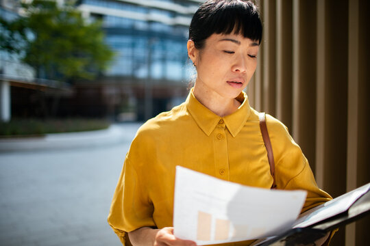 Businesswoman reviewing documents outdoors in city