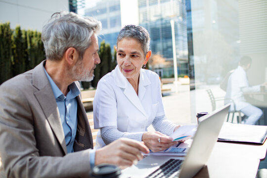 Healthcare professional consulting senior man outdoors at modern office