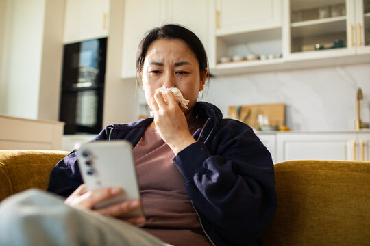Sick woman using smartphone for telehealth at home