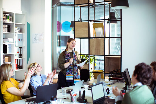 Team applauds female colleague during office presentation