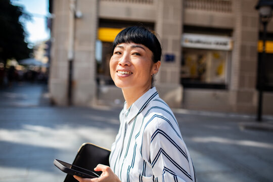 Smiling woman using smartphone on city street