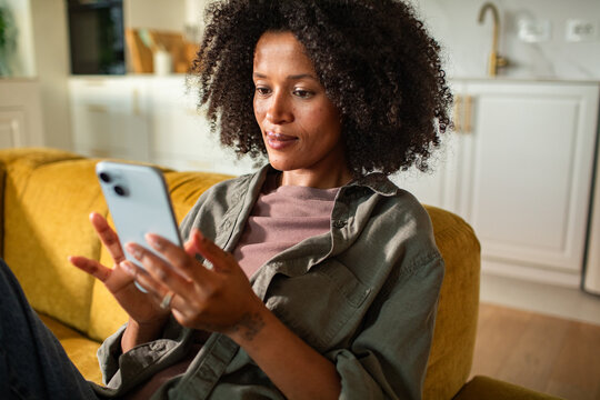 Woman using smartphone on sofa at home