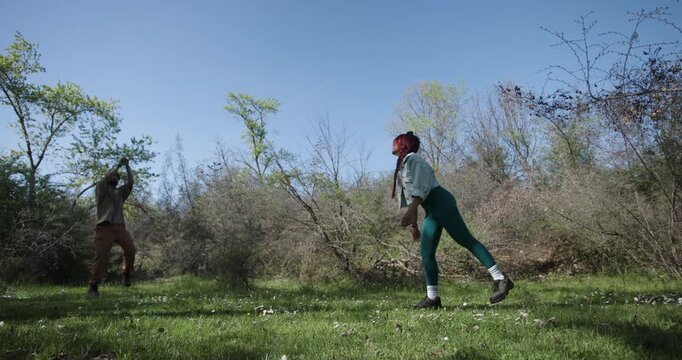 Couple Playing Frisbee in a Sunny Meadow on a Beautiful Spring Day
