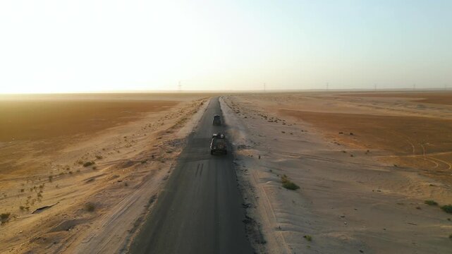 Aerial Drone Shot of Two 4x4 Vehicles Driving on Desert Road at Sunrise