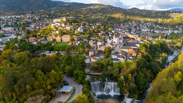 Aerial view of the historic town of Jajce featuring the iconic Pliva Waterfall, the medieval Jajce Fortress, and surrounding lush hills in Jajce, Federation of Bosnia, Bosnia and Herzegovina.