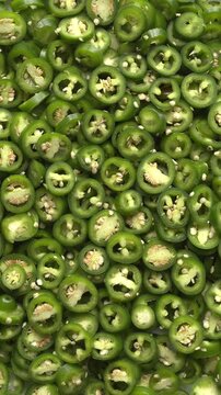 Sliced, green, unripe jalape&ntilde;o as background texture. Top view of freshly harvested organic chilies from your own garden. Table spin, vertical video, natural light.