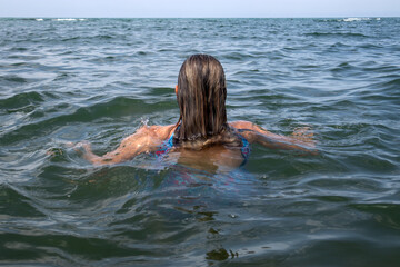 Donna di spalle che nuota e galleggia nel mare aperto e calmo durante una giornata estiva di relax © Ilarialapreziosa