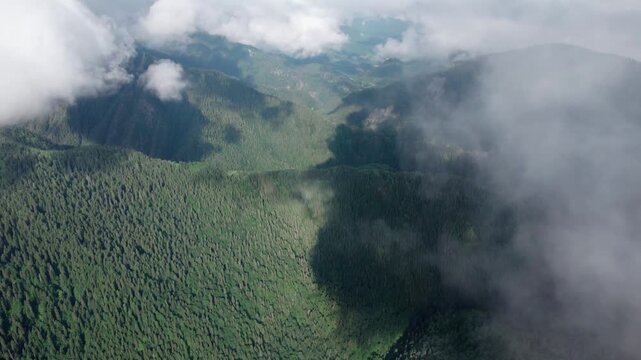 Aerial drone flight through clouds above lush green Caucasus mountains in Svaneti, Georgia. Peaceful alpine landscape with forested peaks, perfect for meditation, relaxation, travel and nature project