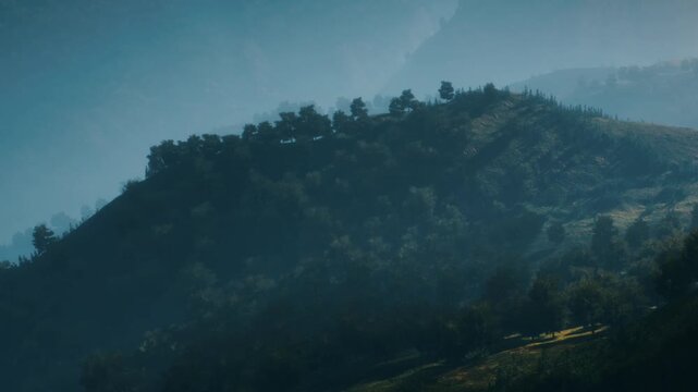 The scene shows a range of mountains partially hidden by fog. Trees are scattered across the slopes. Light is seen breaking through in some areas. The setting appears quiet and untouched.