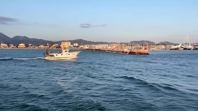 The fisherman boat come back at port at sunset panoramic view pier of Viareggio, Italy	
