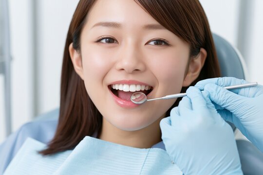 歯科検診で口を開けて診察を受ける若い日本人女性の笑顔