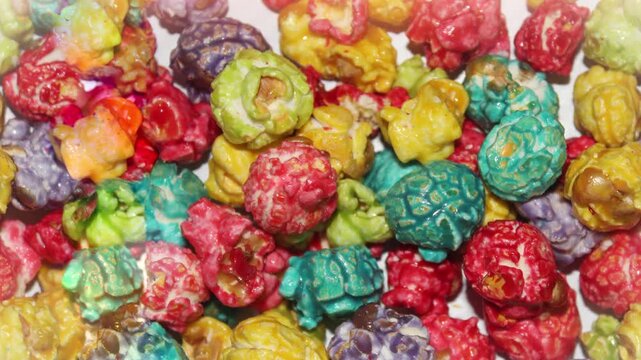 Seamless 4K looping vertical movement across colorful caramel popcorn with vibrant candy coating. Perfect for festive food backgrounds celebrations and creative projects.