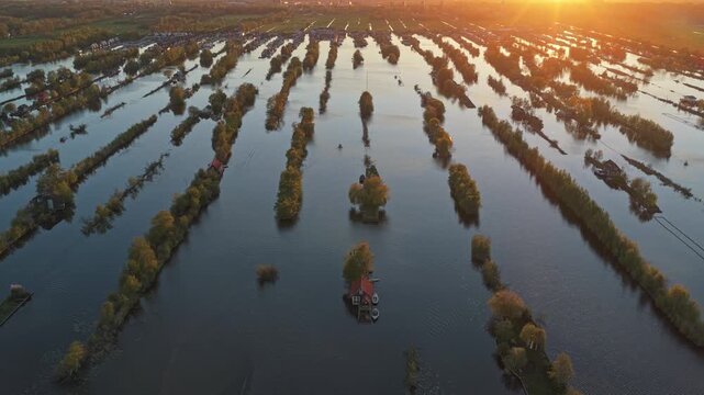 Drone flying backwards over dutch peatlands landscape at sunset