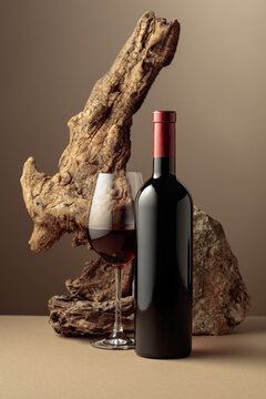 Glass and bottle of red wine with old driftwood and a piece of granite rock.