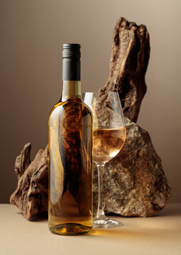 Glass and bottle of white wine with old driftwood and a piece of granite rock.