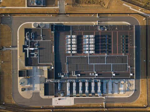 Aerial view of a hyperscale data center featuring rows of rooftop cooling units and ventilation systems under warm golden hour light in Didcot, England, United Kingdom.
