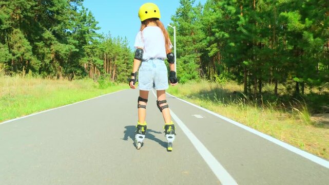Carefree positive adorable girl roller skating in public park. Joyful child having fun, enjoying rollerblading outdoors on summer day