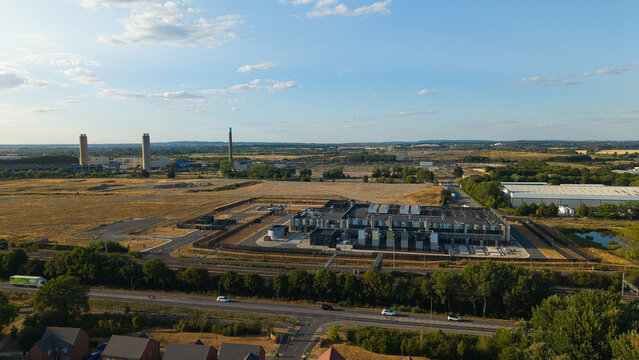 Aerial view of the Hyperscale Data Center during golden hour, featuring modern industrial architecture, surrounding fields, and nearby power station chimneys in Didcot, England, United Kingdom.