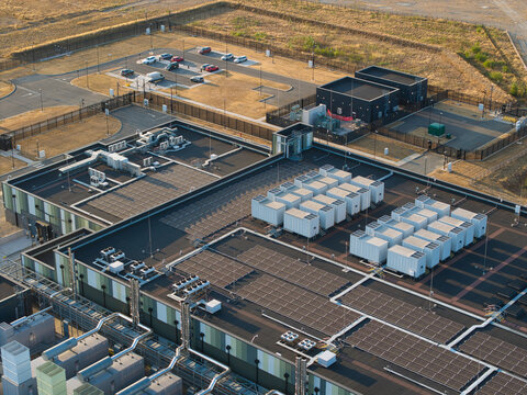 Aerial view of a hyperscale data center featuring rows of cooling units, solar panels, and a parking lot during golden hour in Didcot, England, United Kingdom.