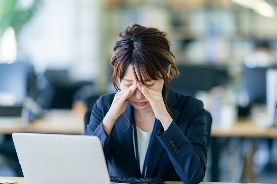 仕事で疲れたビジネスウーマン残業によるストレスと頭痛に悩む