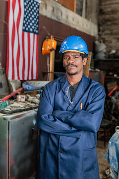 African American worker stands in workshop with American flag