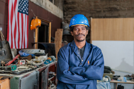 African American worker stands in workshop with American flag