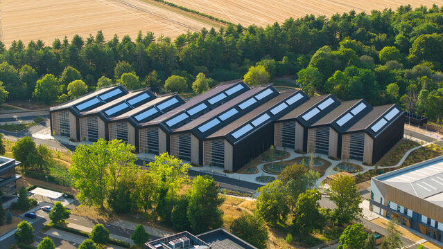 Aerial view of the Harwell Science and Innovation Campus featuring the tech foundry 3 building with its sawtooth solar roof, surrounded by trees in Didcot, England, United Kingdom.