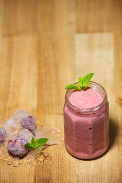 Fresh strawberry smoothie in glass jar with ice mint on wooden background